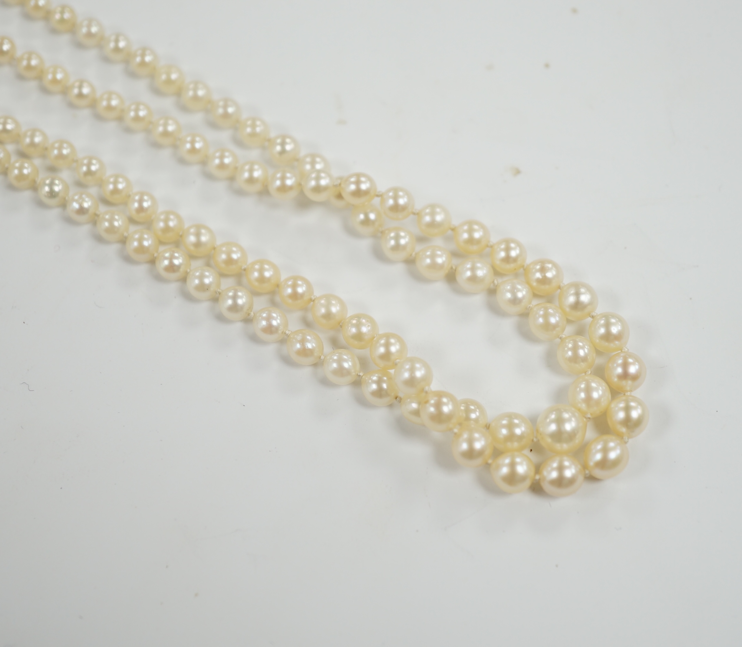 A 1930's twin strand graduated cultured pearl necklace, with 14ct, plat and diamond chip set clasp, 50cm.